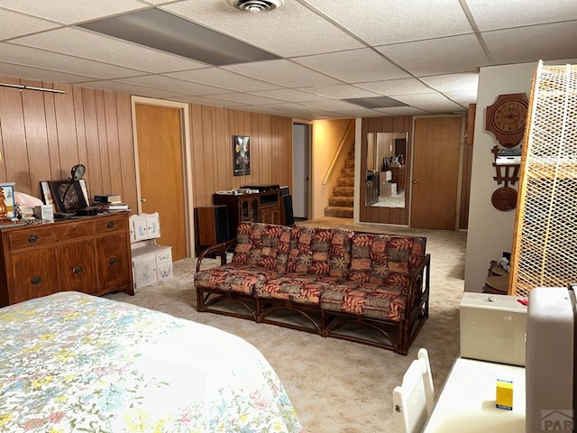 carpeted bedroom featuring wood walls, a drop ceiling, and visible vents