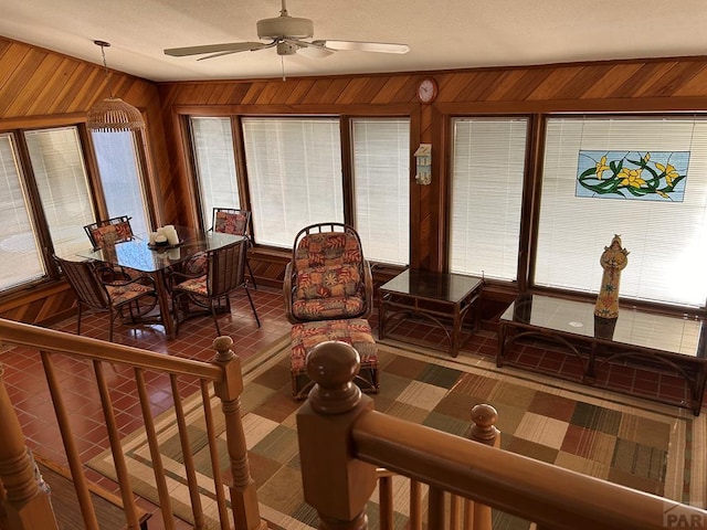 interior space with wood walls and a ceiling fan