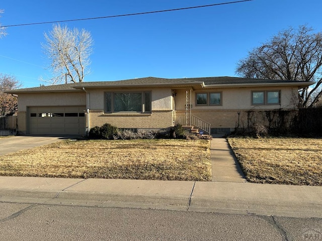 view of front of house featuring a garage, brick siding, driveway, and stucco siding