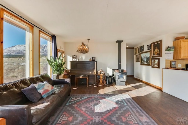 living area featuring dark wood-style flooring, a wood stove, and baseboards