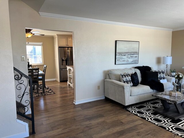 living room featuring a ceiling fan, crown molding, baseboards, and dark wood-type flooring