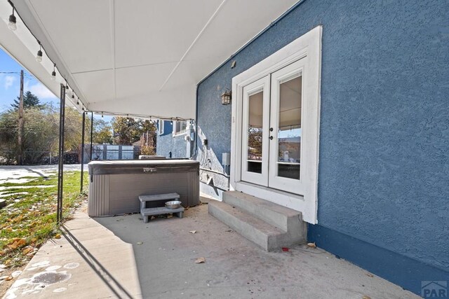 view of patio with entry steps, french doors, fence, and a hot tub