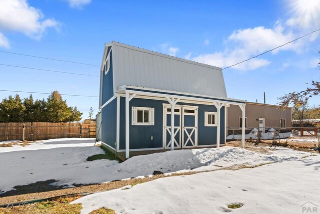 snow covered garage with fence