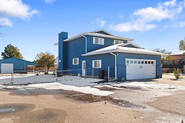 view of front of home with concrete driveway, a chimney, an attached garage, and fence