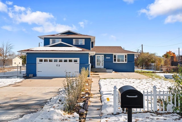 view of front of house with driveway, brick siding, a fenced front yard, and an attached garage