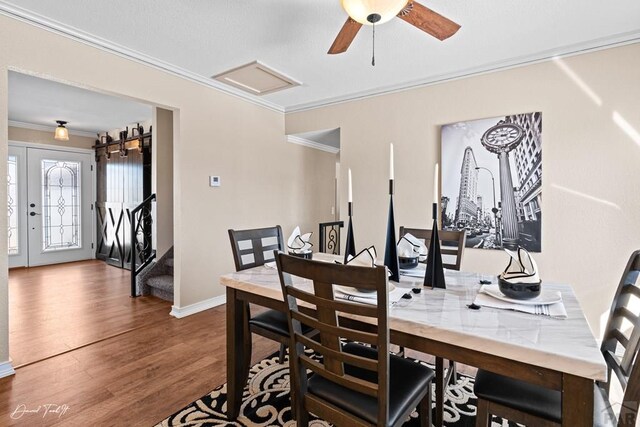 dining space featuring attic access, baseboards, dark wood-style floors, stairway, and ornamental molding