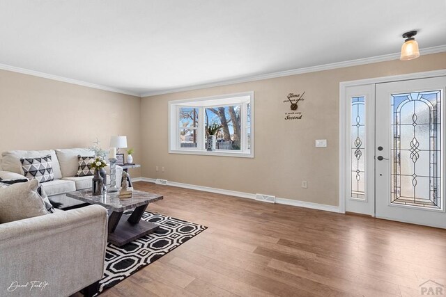 living area featuring ornamental molding, visible vents, baseboards, and wood finished floors