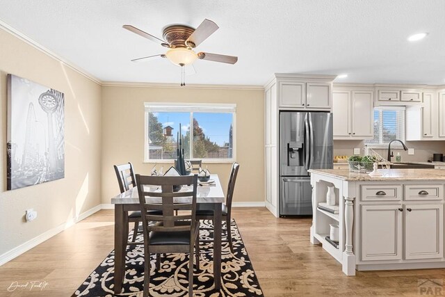 dining area featuring baseboards, light wood-style floors, and crown molding