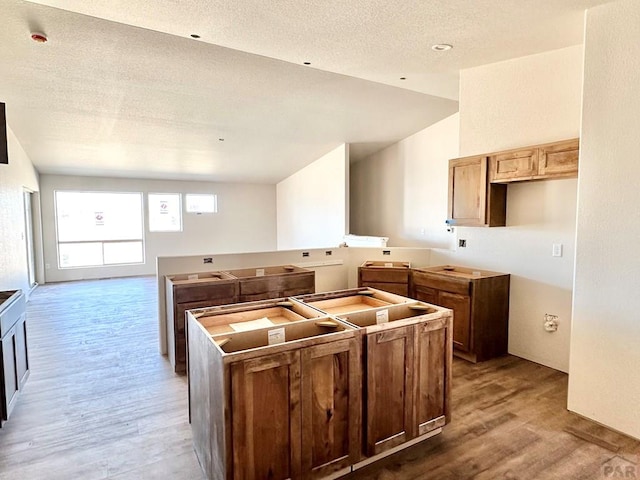 kitchen featuring lofted ceiling, a textured ceiling, wood finished floors, and a center island