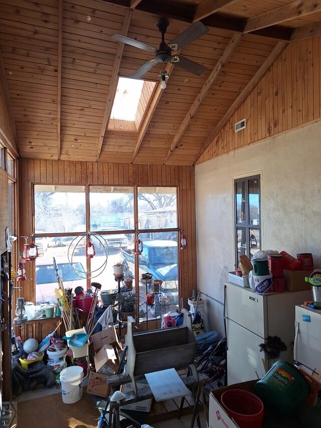 interior space featuring vaulted ceiling with skylight, wood ceiling, and wood walls