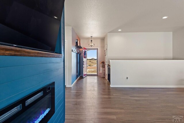 hall featuring dark wood-style floors, a textured ceiling, recessed lighting, and baseboards