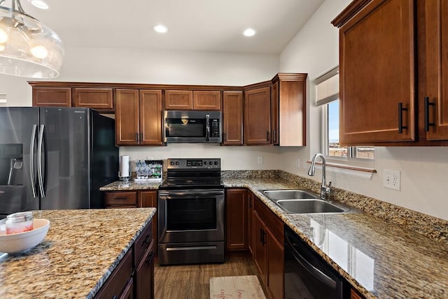 kitchen featuring light stone counters, recessed lighting, stainless steel appliances, a sink, and hanging light fixtures