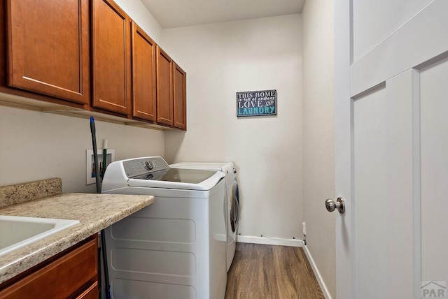 washroom featuring cabinet space, washing machine and dryer, baseboards, and wood finished floors