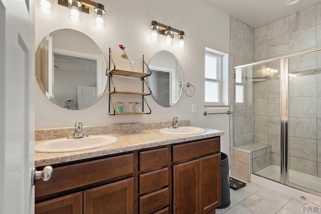 bathroom featuring double vanity, a stall shower, a sink, and tile patterned floors