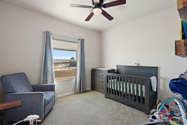 bedroom with a nursery area, light carpet, ceiling fan, and baseboards