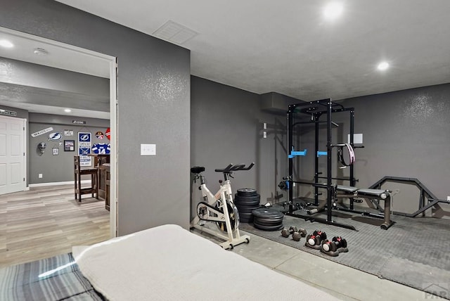 exercise area with recessed lighting, a textured wall, baseboards, and wood finished floors