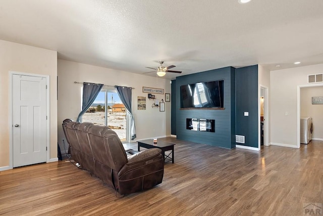 living room with washer / dryer, visible vents, a fireplace, and wood finished floors