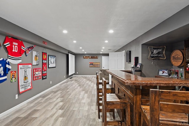 bar featuring recessed lighting, baseboards, light wood finished floors, and a dry bar