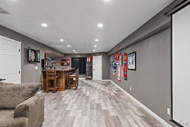 bar featuring a dry bar, visible vents, baseboards, light wood-style flooring, and recessed lighting