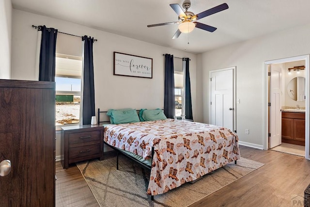 bedroom featuring a sink, light wood-style flooring, baseboards, and ensuite bathroom