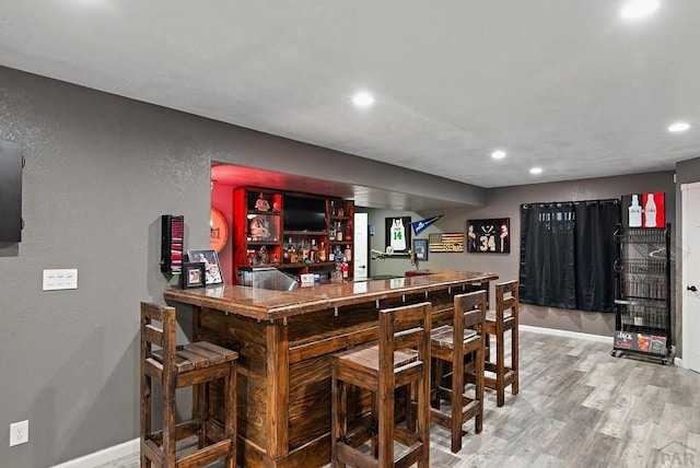 bar featuring recessed lighting, baseboards, a dry bar, and wood finished floors