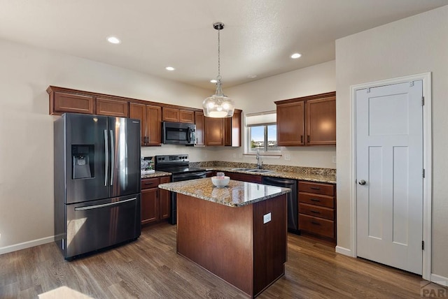 kitchen with stainless steel appliances, a sink, a kitchen island, light stone countertops, and pendant lighting