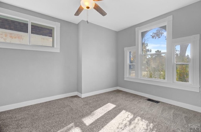 carpeted spare room with a ceiling fan, visible vents, and baseboards