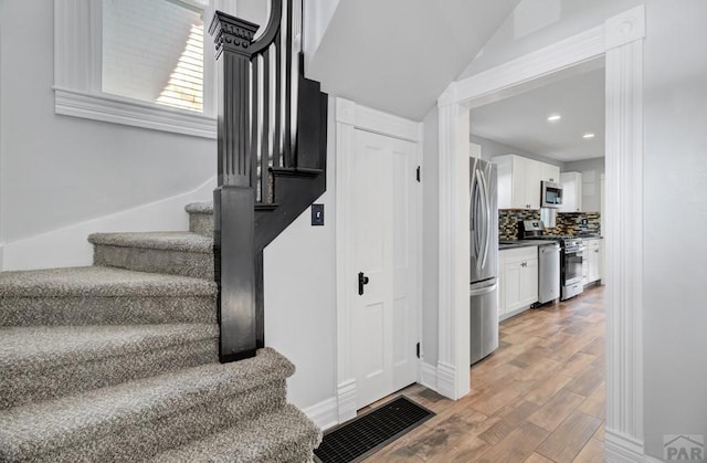 stairs featuring wood finished floors and recessed lighting