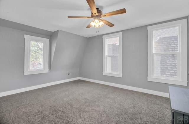 carpeted spare room featuring a ceiling fan and baseboards