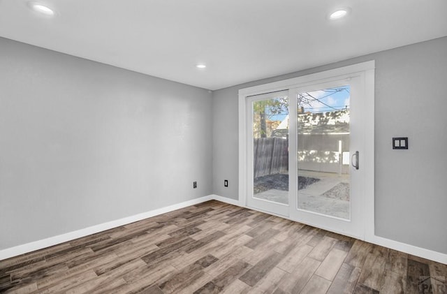 unfurnished room with recessed lighting, wood finished floors, and baseboards