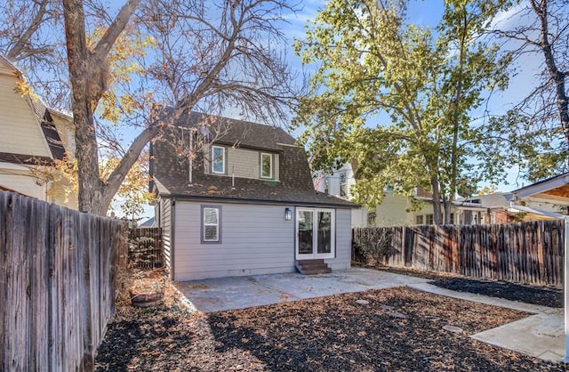 rear view of house with entry steps, a patio, roof with shingles, and a fenced backyard