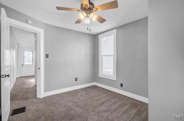 carpeted empty room featuring ceiling fan, visible vents, and baseboards