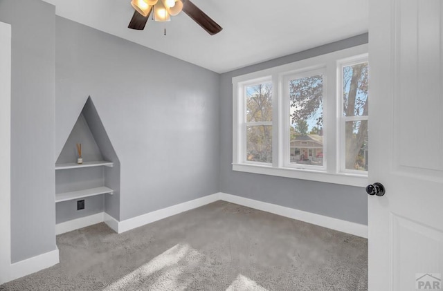 interior space featuring built in shelves, baseboards, and a ceiling fan