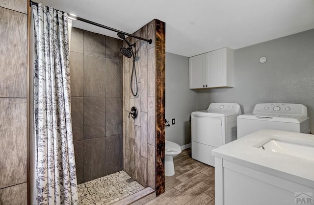 bathroom featuring toilet, wood finish floors, vanity, a shower stall, and washing machine and clothes dryer