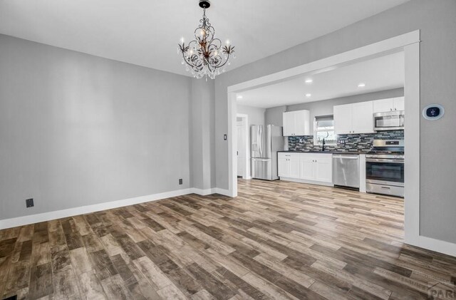 kitchen featuring white cabinetry, appliances with stainless steel finishes, decorative backsplash, dark countertops, and decorative light fixtures