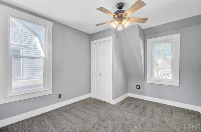 bonus room featuring baseboards, dark carpet, and a ceiling fan