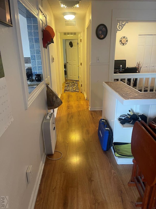 corridor with visible vents, baseboards, and wood finished floors