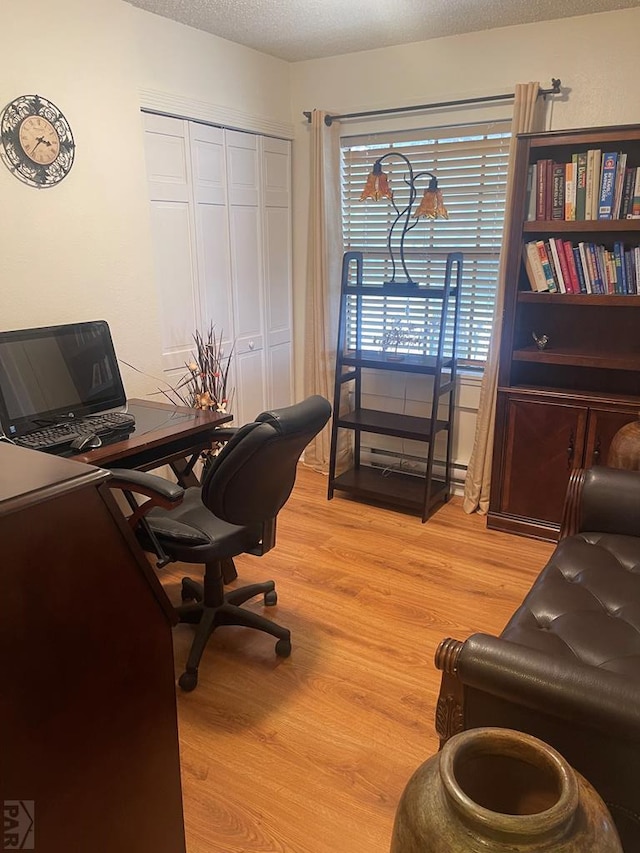 office area with light wood-type flooring and a textured ceiling