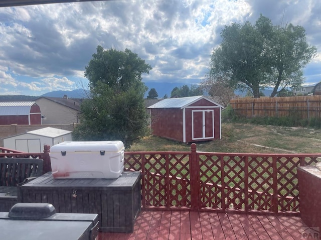 wooden deck featuring a storage shed, fence, and an outdoor structure