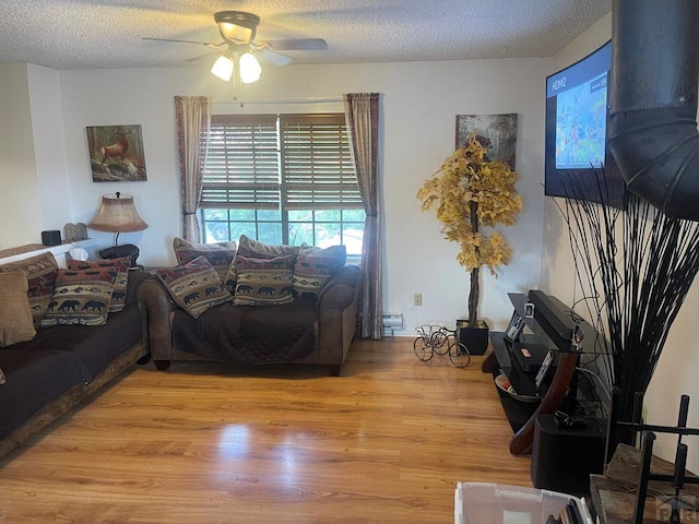 living area featuring a textured ceiling, light wood-style floors, and a ceiling fan