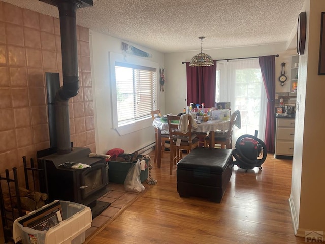 dining area with a wealth of natural light, a textured ceiling, a wood stove, and wood finished floors