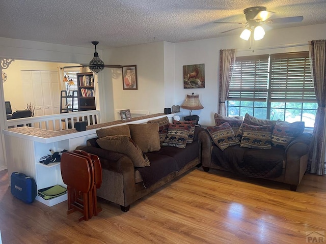 living room with ceiling fan, wood finished floors, and a textured ceiling