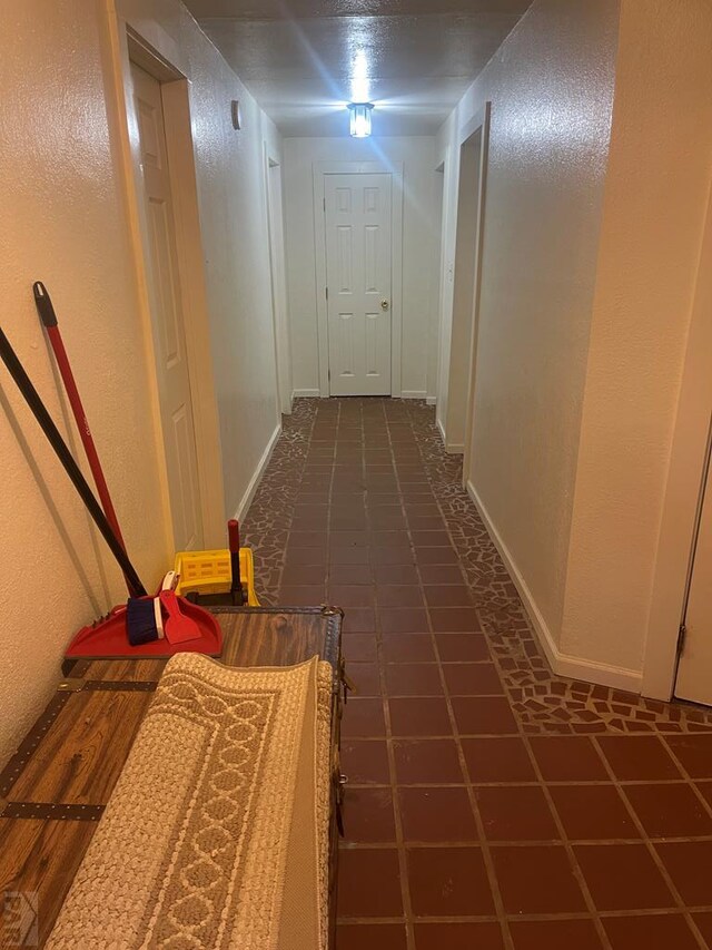 hall with baseboards and a textured wall