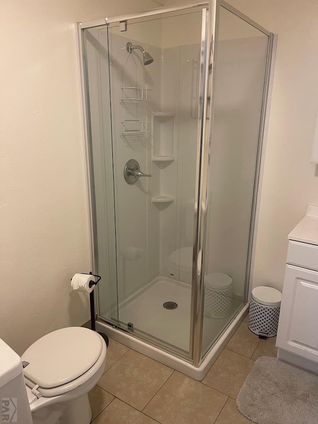 bathroom featuring tile patterned floors, toilet, a stall shower, and vanity