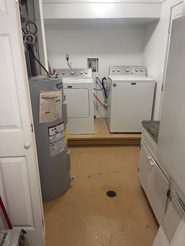 washroom featuring cabinet space, water heater, and washer and clothes dryer