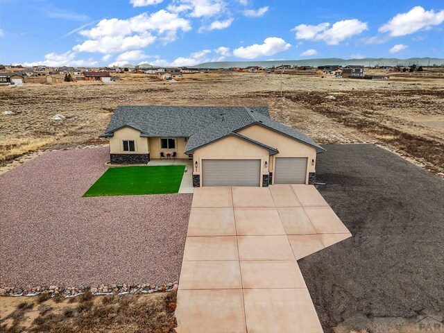 view of front of home with a mountain view, a garage, a shingled roof, driveway, and stucco siding