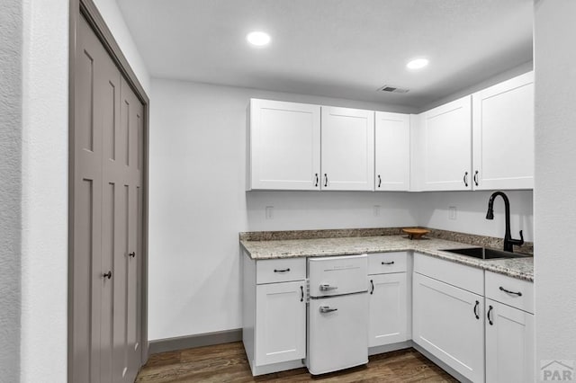 kitchen featuring dark wood-style floors, recessed lighting, white cabinets, a sink, and light stone countertops