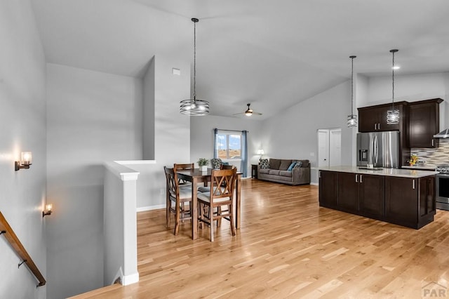 dining room featuring baseboards, high vaulted ceiling, a ceiling fan, and light wood-style floors