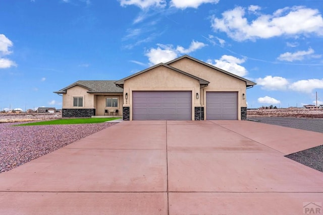 view of front of home featuring a garage, stone siding, driveway, and stucco siding