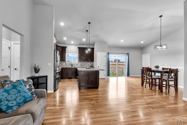 kitchen featuring open floor plan, hanging light fixtures, a kitchen island, and dark brown cabinetry